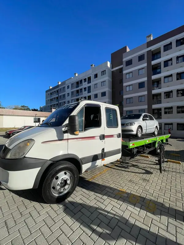 Guincho com carro prata na plataforma em condomínio